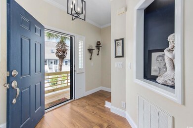 Entryway with an inviting chandelier, hardwood / wood-style flooring, and ornamental molding