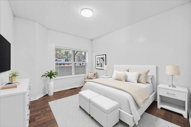 Bedroom with dark wood-style floors, visible vent