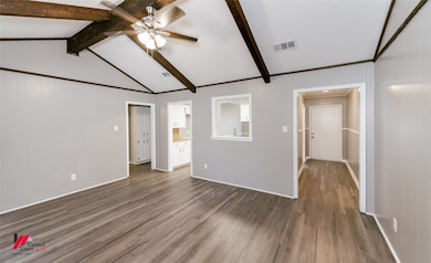 Unfurnished living room featuring wood finished floors, a ceiling fan, and wood walls