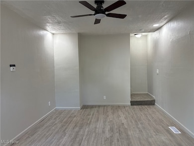 Unfurnished room featuring light wood-style floors, a textured ceiling, and a ceiling fan