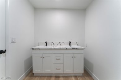 Full bathroom with double vanity and light wood-type flooring