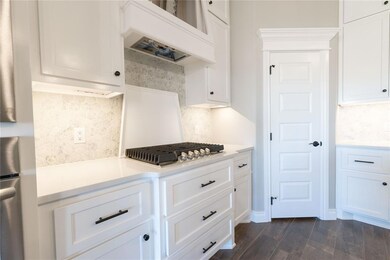 Kitchen with a sink, white cabinetry, dark wood-st