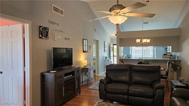 Living room with dark wood-style floors, a chandel