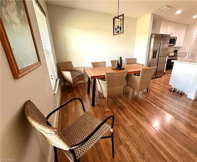 Stylish dining area featuring light wood-style floors, seamlessly integrated into the great room with open views of the kitchen, living space, and warm, welcoming foyer—ideal for both casual meals and elegant entertaining.flooring and recessed lighting