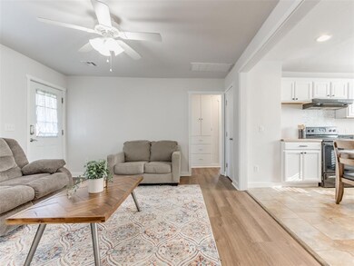 Living room with ceiling fan and light wood-type f