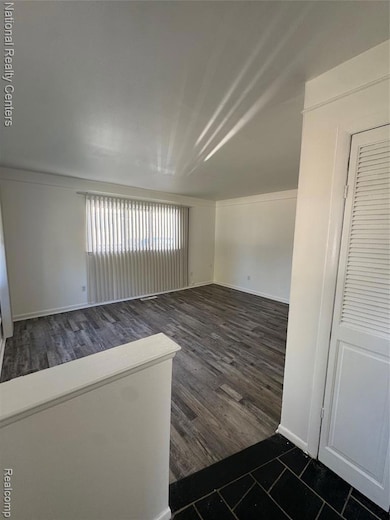 Empty room with baseboards and dark wood-style floors