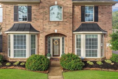 A traditional style exterior with a brick exterior and charming metal dormers accents above the windows adds such timeless character!  Blooming foliage lines the walkway to the door!