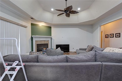 Living area featuring ceiling fan, crown molding, a fireplace, and a raised ceiling