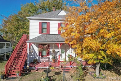 View of front of property featuring a shingled roof, a chimney, and stairs