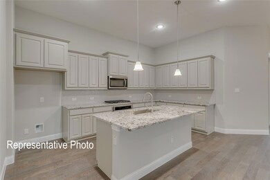 Kitchen featuring light stone countertops, appliances with stainless steel finishes, sink, hanging light fixtures, and an island with sink