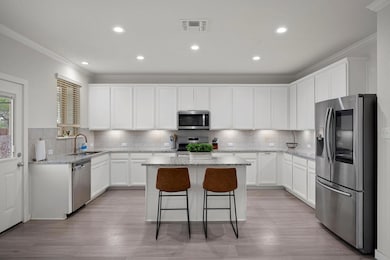 Kitchen with a kitchen breakfast bar, stainless steel appliances, ornamental molding, a kitchen island, and a sink