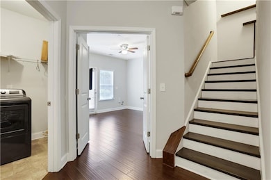Staircase featuring washer / dryer, baseboards, ceiling fan, and wood finished floors