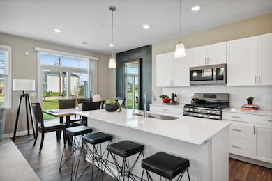 Spacious kitchen with large island, quartz countertops, tile backsplash, white cabinets, pull out trash/recycling cabinet and the popular slate finish appliances! *Photos of model home; colors and finishes will vary.