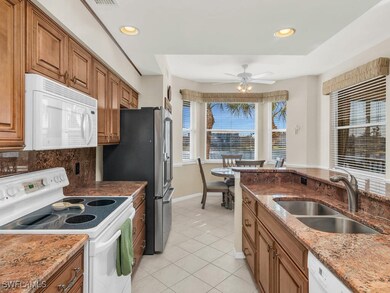 Kitchen with white appliances, a sink, light tile