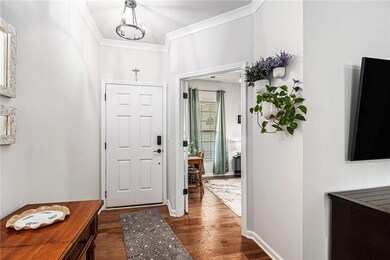Entryway featuring dark wood finished floors, ornamental molding, a chandelier, and baseboards