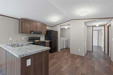 Kitchen featuring black appliances, dark wood-style flooring, light countertops, a textured ceiling, and washer and dryer