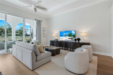Living area with wood finished floors, ornamental molding, a tray ceiling, and a ceiling fan