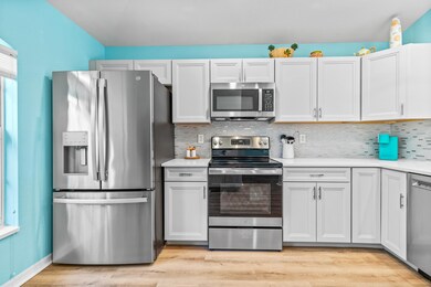 Kitchen with appliances with stainless steel finishes, backsplash, light wood-style flooring, and white cabinetry