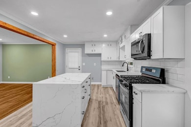 Kitchen featuring stainless steel appliances, a sink, light wood finished floors, recessed lighting, and white cabinetry
