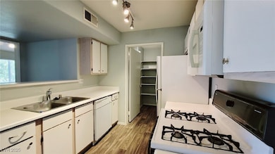 Kitchen featuring white appliances, a sink, light