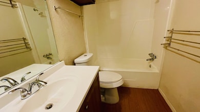 Bathroom with dark wood finished floors, bathtub / shower combination, vanity, and a textured wall