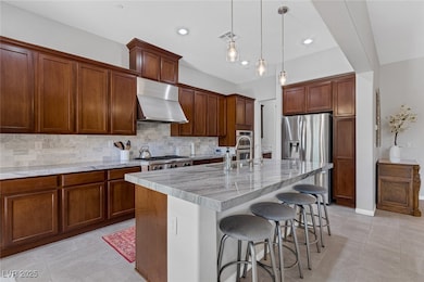 Kitchen with a kitchen bar, extractor fan, tasteful backsplash, hanging light fixtures, and an island with sink