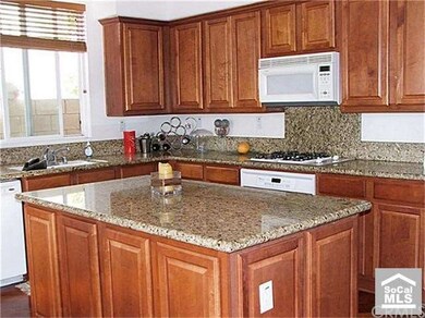 Gleaming kitchen features elegant granite slab cou
