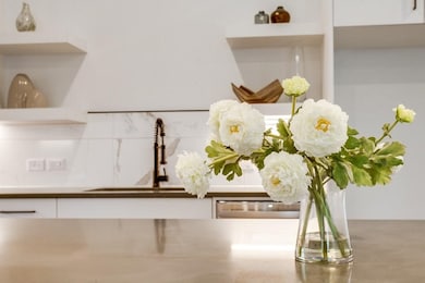 Kitchen view of open shelves, white cabinets, and decorative backsplash