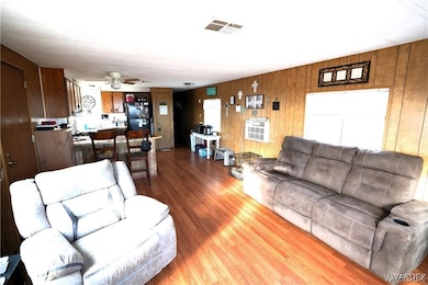 Living room with ceiling fan, wooden walls, and wo