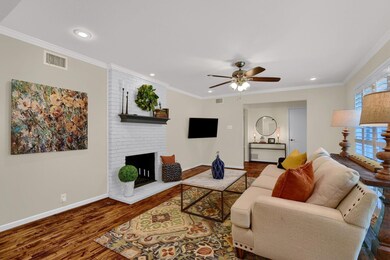 Living room featuring ceiling fan, a wealth of natural light, a fireplace, and dark hardwood / wood-style floors