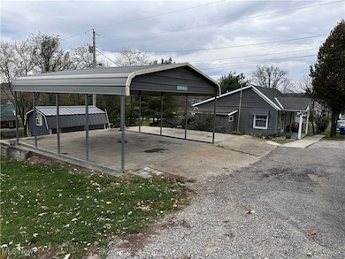 View of parking / parking lot featuring a carport and driveway