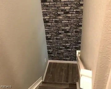 Stairway featuring wood finished floors and a textured wall