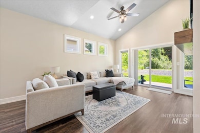 Living room with a ceiling fan, high vaulted ceiling, dark wood-type flooring, and recessed lighting
