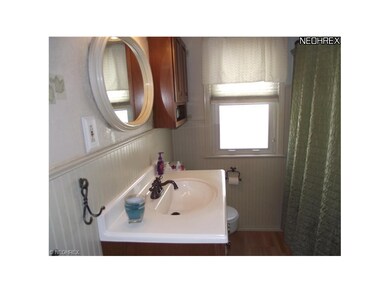 The main bath carries the decorating theme from the kitchen with wainscoting and laminate floors.