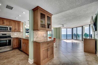 Kitchen featuring stainless steel appliances, open floor plan, decorative backsplash, light stone counters, and a textured ceiling