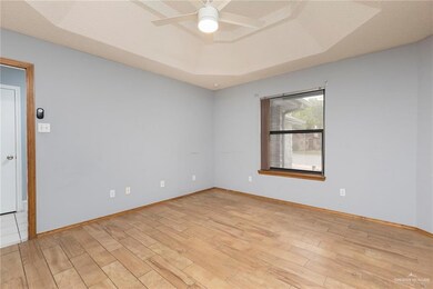 Empty room with light wood-type flooring, a raised ceiling, ceiling fan, and baseboards