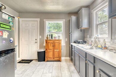 Kitchen with gray cabinetry, freestanding refrigerator, light countertops, and decorative backsplash