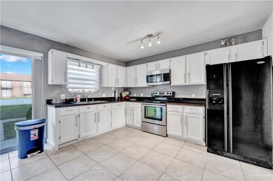 Kitchen with stainless steel appliances, a sink, white cabinetry, and light tile patterned floors