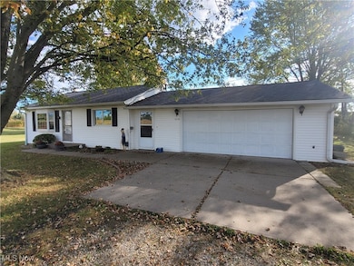 Ranch-style house featuring concrete driveway, a front lawn, and a garage