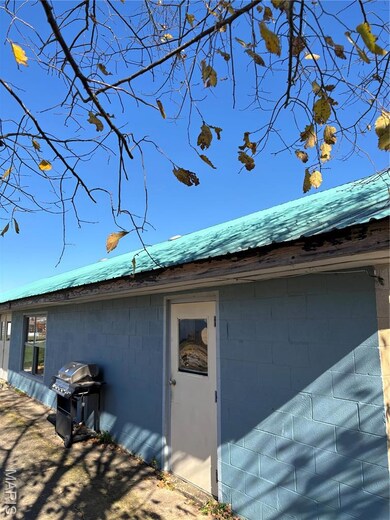 View of property exterior with a metal roof and concrete block siding