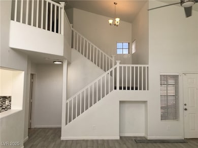 Stairway with a high ceiling, wood finished floors, and a chandelier