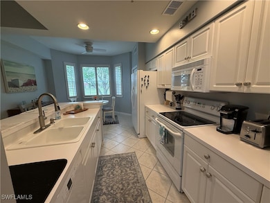 Kitchen featuring white appliances, a sink, light