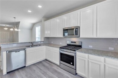 Kitchen with stainless steel appliances, white cabinetry, a peninsula, light stone counters, and recessed lighting