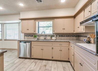 Kitchen with backsplash, a textured ceiling, sink, light wood-type flooring, and stainless steel dishwasher