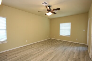 Living area has wood-plank tile flooring, ceiling fan and window blinds.