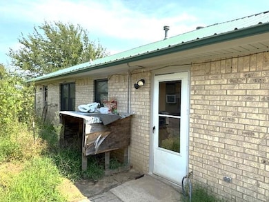 View of exterior entry with brick siding and a metal roof