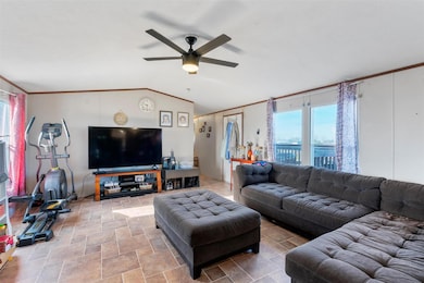 Living room with crown molding, lofted ceiling, and a ceiling fan