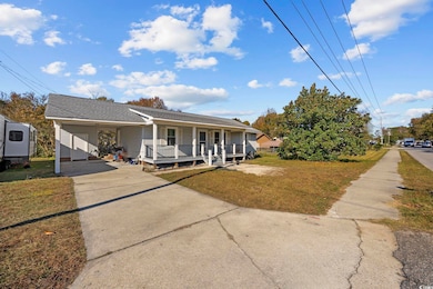 Bungalow-style home with roof with shingles, covered porch, concrete driveway, a front yard, and a carport