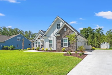 View of front of property with board and batten siding, driveway, a garage, a storage unit, and a front yard