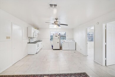 Kitchen with ceiling fan, white cabinets, light ti
